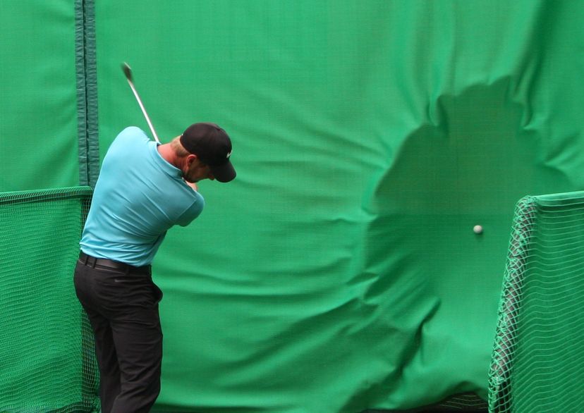 golfer hitting ball into golf baffle net