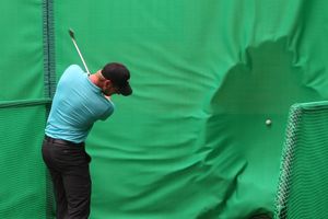 golfer hitting ball into golf baffle net