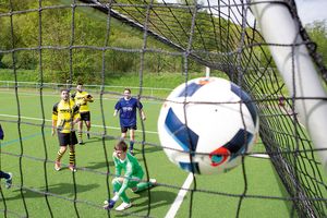 Ball der in Ultra Fußballtornetz fliegt mit 5 Spielern im Hintergrund