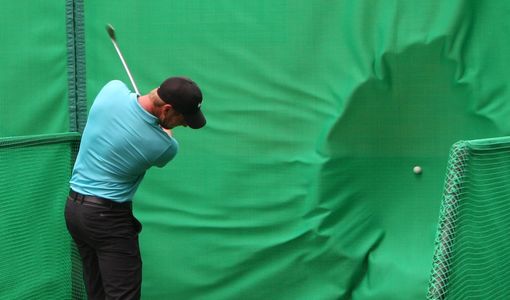 golfer hitting ball into golf baffle net